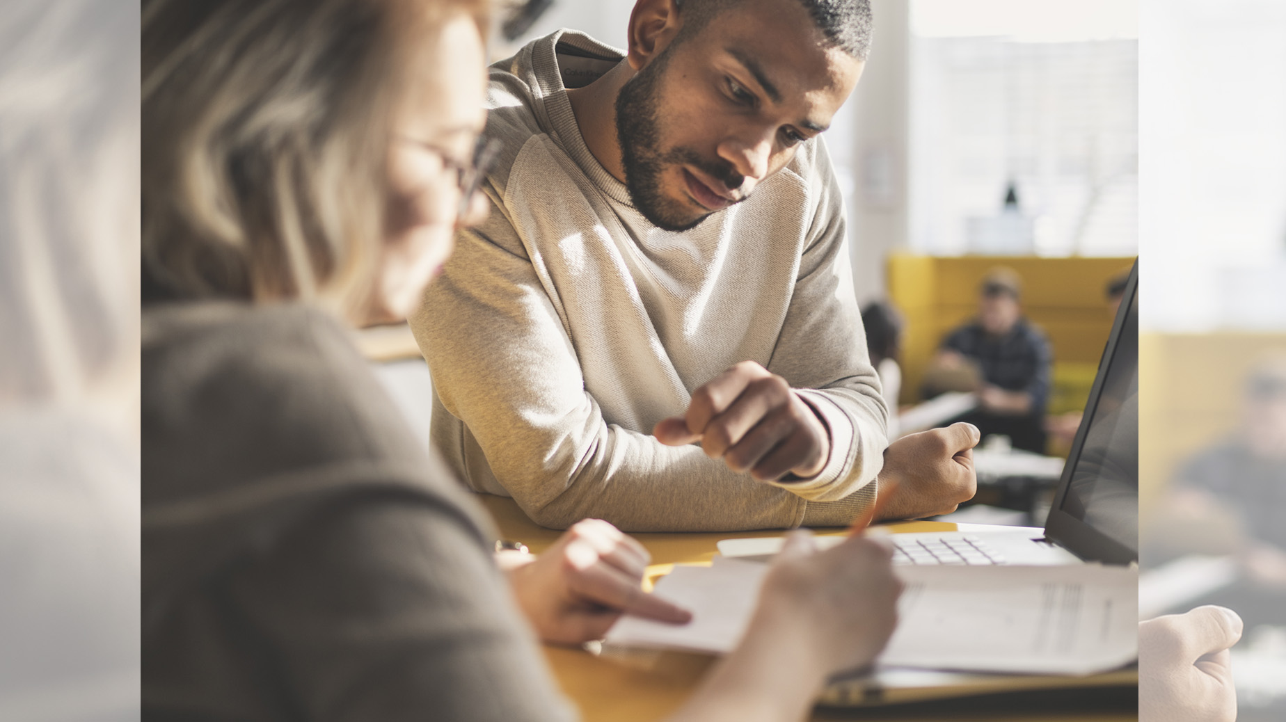 En kvinna och en man sitter vid ett bord. På bordet finns dokument. I bakgrunden finns ett fönster. Foto: Istock